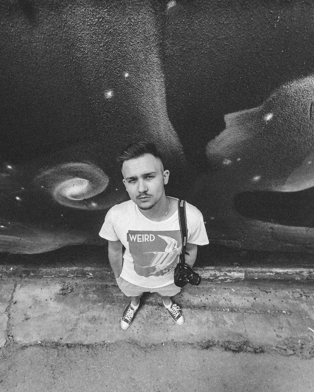 Nebojsa standing in front of a galaxy mural with a camera on his shoulder